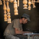 A man sitting at a table working on a piece of wood