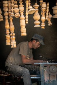 A man sitting at a table working on a piece of wood